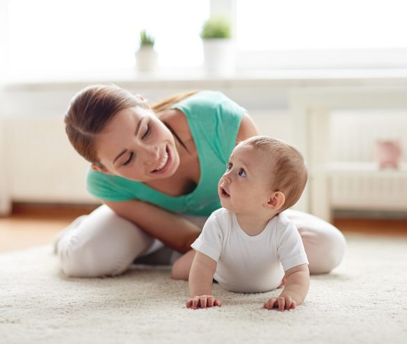 family, child and parenthood concept - happy smiling young mother playing with little baby at home